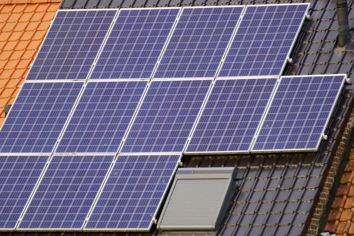 Solar panels fitted around a roof window on a tiled roof